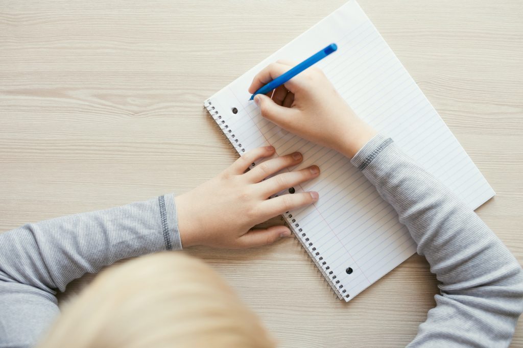 Kid Writing in Notebook.